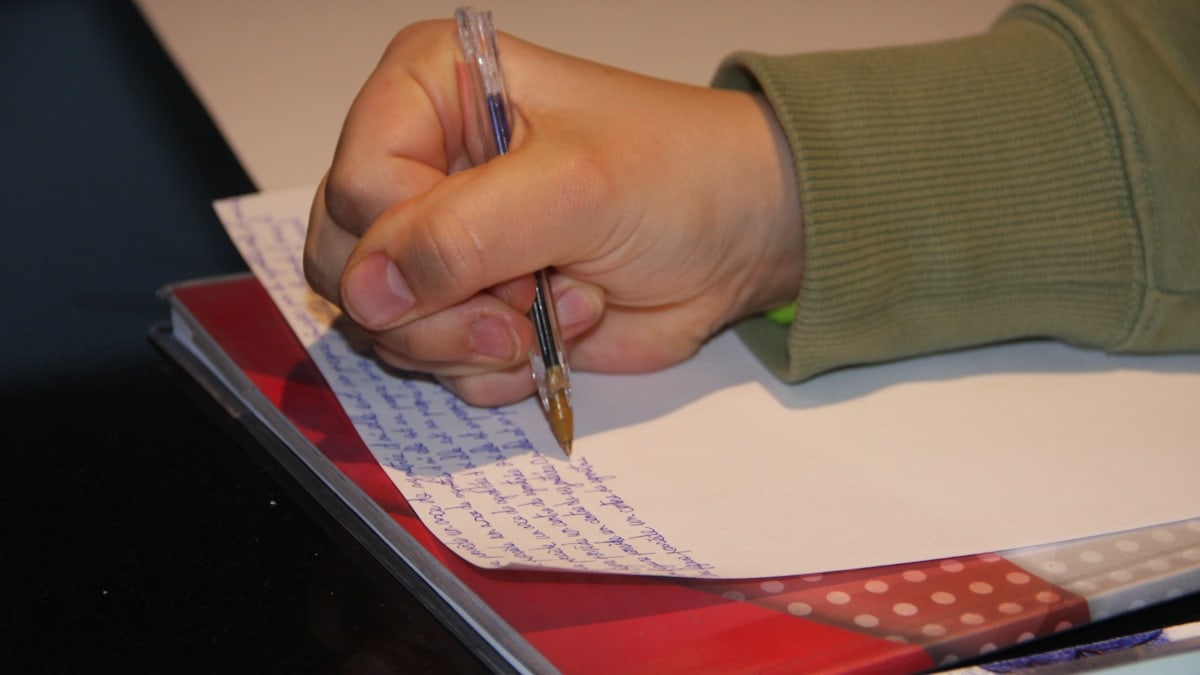 Personne étudiant son cours sur une table noire.